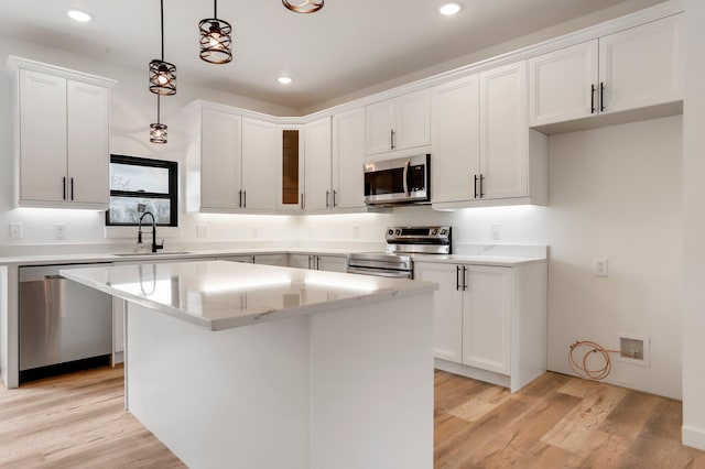000 State Route Jj, West Plains, MO 65775 - kitchen with a sink, decorative light fixtures, a kitchen island, appliances with stainless steel finishes, and white cabinetry