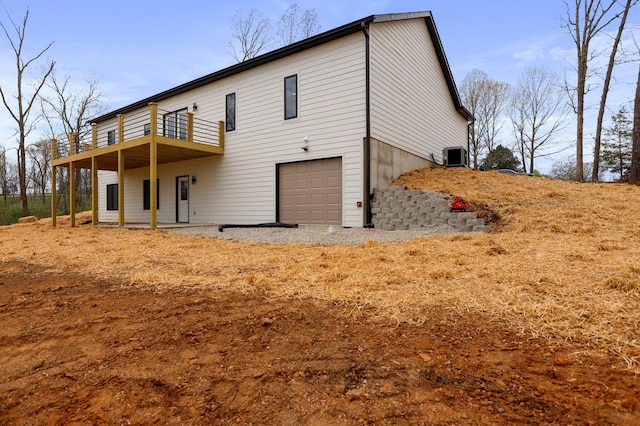 back of property with a garage, a wooden deck, and central AC