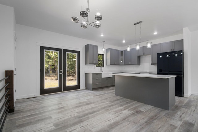 kitchen with a center island, black fridge, light hardwood / wood-style flooring, and gray cabinetry