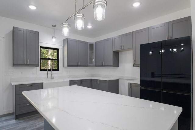 kitchen featuring gray cabinetry, pendant lighting, light stone counters, sink, and dark hardwood / wood-style floors