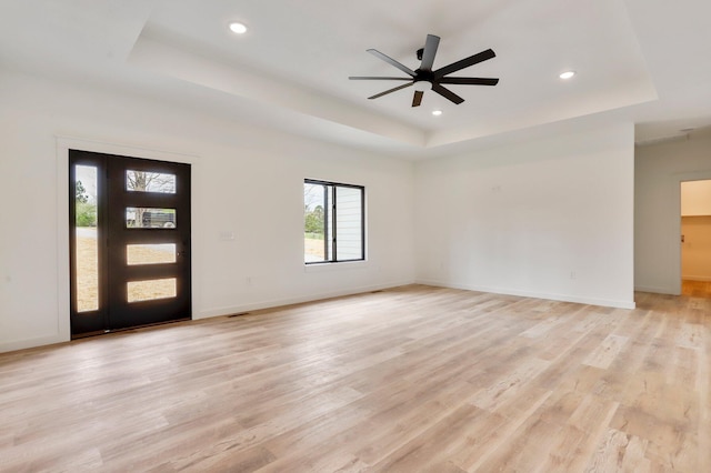 entryway featuring ceiling fan, a tray ceiling, and light hardwood / wood-style floors