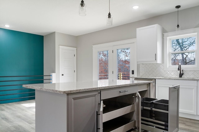 kitchen with pendant lighting, white cabinetry, beverage cooler, and light wood-type flooring