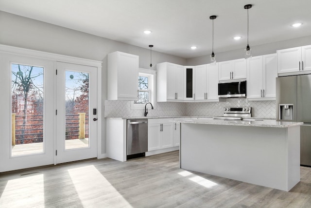 kitchen featuring white cabinets, appliances with stainless steel finishes, light hardwood / wood-style floors, and a center island