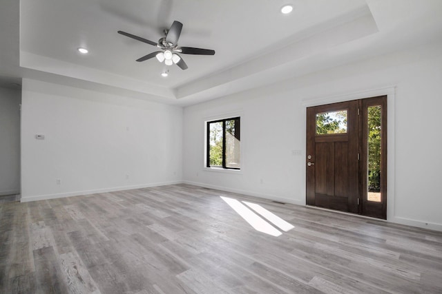 interior space featuring ceiling fan, a tray ceiling, and light hardwood / wood-style floors