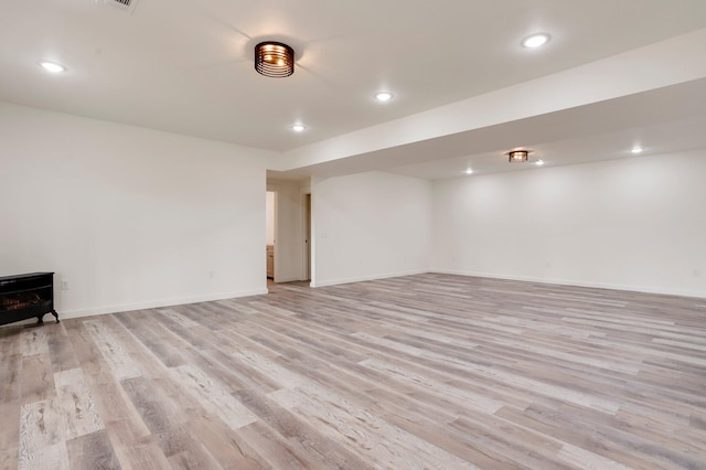 basement with light hardwood / wood-style floors and a wood stove