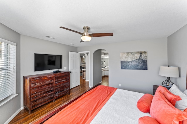 bedroom featuring a textured ceiling, ensuite bath, ceiling fan, and dark hardwood / wood-style flooring