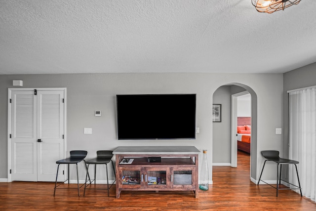 living room featuring dark wood-type flooring and a textured ceiling