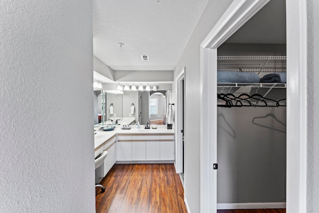 bathroom with wood-type flooring, vanity, and a textured ceiling