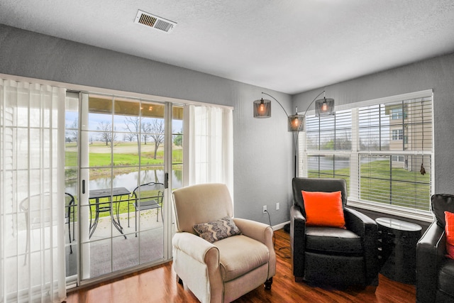 living area featuring wood-type flooring, a textured ceiling, a water view, and a wealth of natural light