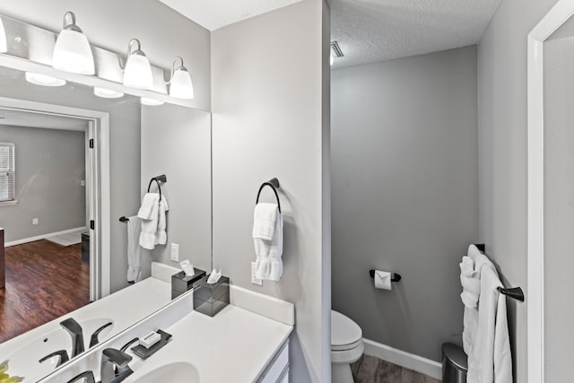 bathroom featuring hardwood / wood-style floors, vanity, a textured ceiling, and toilet