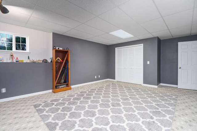 basement with a paneled ceiling and carpet flooring