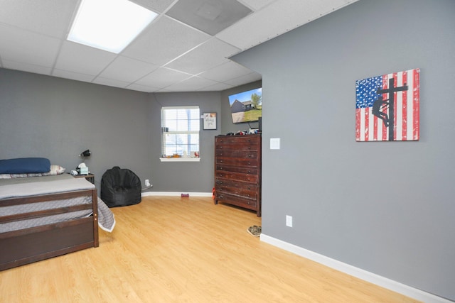 bedroom with a paneled ceiling and wood-type flooring