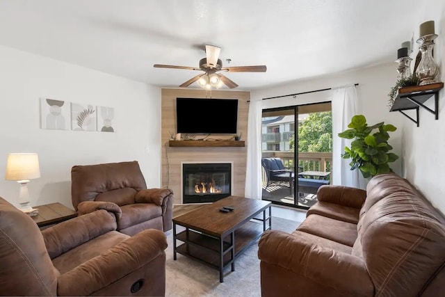 living room featuring a large fireplace and ceiling fan