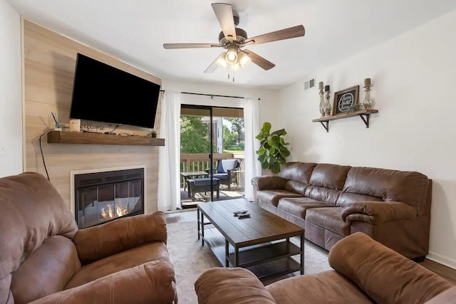 living room featuring hardwood / wood-style flooring, ceiling fan, and a large fireplace