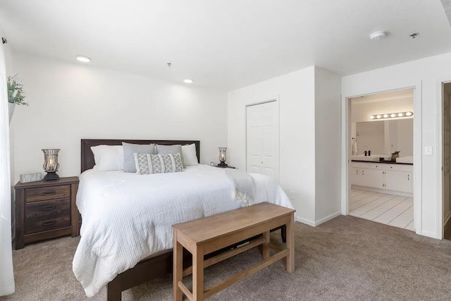 bedroom featuring light colored carpet, a closet, and connected bathroom