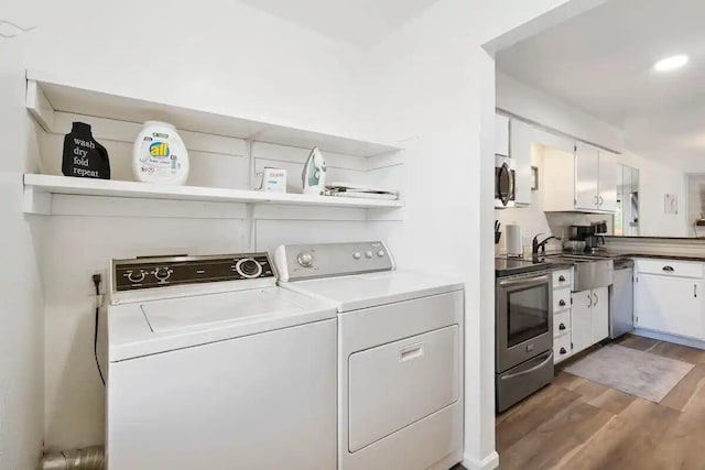 washroom with washing machine and dryer, sink, and dark hardwood / wood-style floors