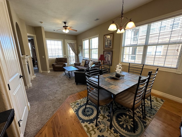 dining space featuring hardwood / wood-style floors, ceiling fan with notable chandelier, and a textured ceiling