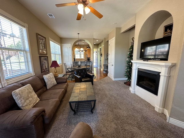 carpeted living room featuring ceiling fan with notable chandelier