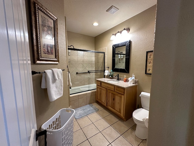 full bathroom with tile patterned flooring, combined bath / shower with glass door, toilet, vanity, and a textured ceiling