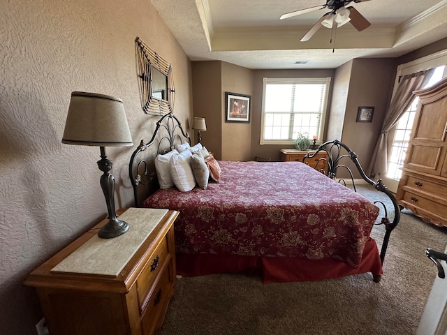 bedroom with ceiling fan, ornamental molding, a raised ceiling, and carpet flooring