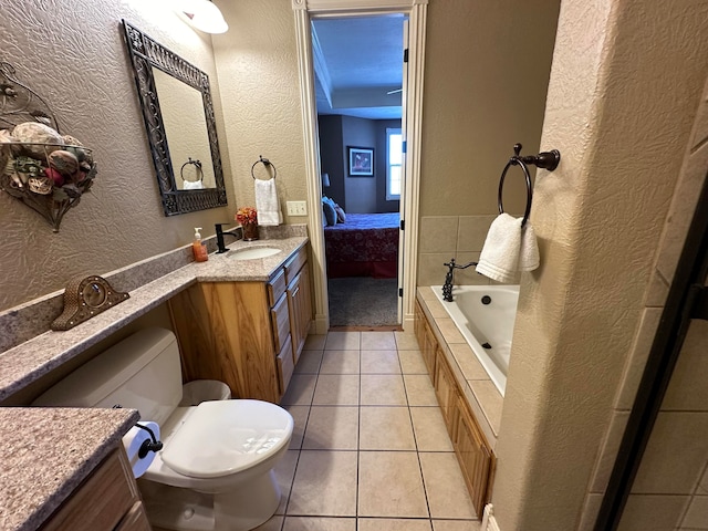 bathroom with tiled bath, tile patterned floors, vanity, and toilet