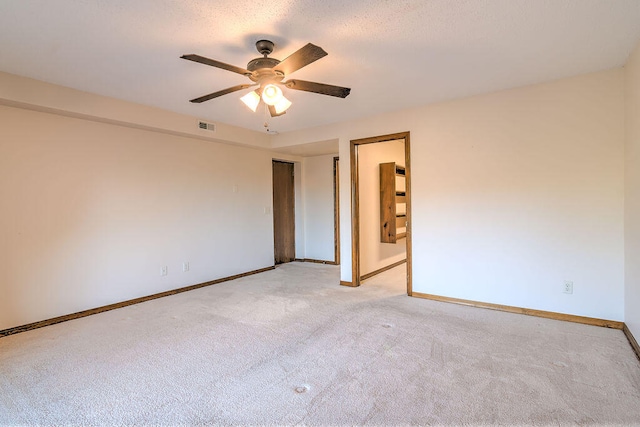 spare room with a textured ceiling, ceiling fan, and light colored carpet