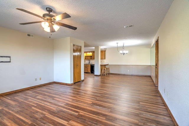 unfurnished living room with a textured ceiling, ceiling fan with notable chandelier, dark hardwood / wood-style floors, and sink