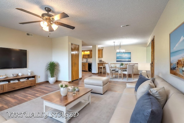 living room featuring light wood-type flooring, ceiling fan, sink, and a textured ceiling