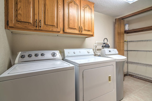 laundry area featuring cabinets, separate washer and dryer, light tile patterned floors, and a textured ceiling