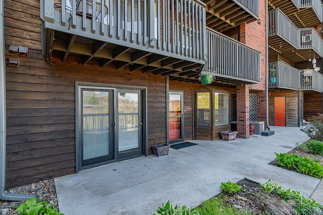 view of exterior entry featuring a patio and a balcony