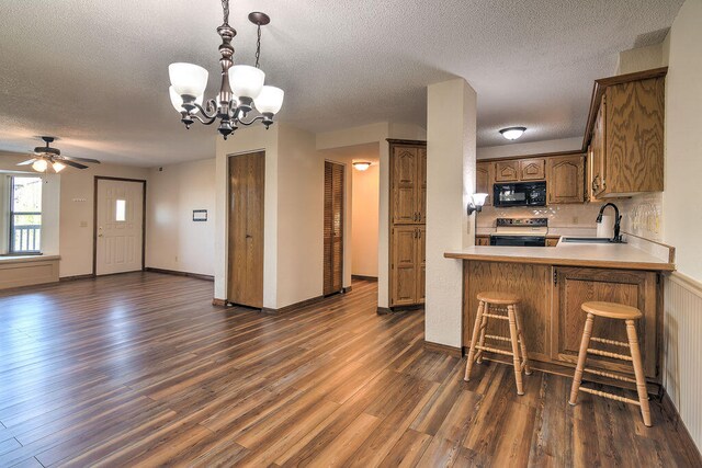 kitchen featuring stainless steel electric range, dark hardwood / wood-style flooring, sink, kitchen peninsula, and a textured ceiling