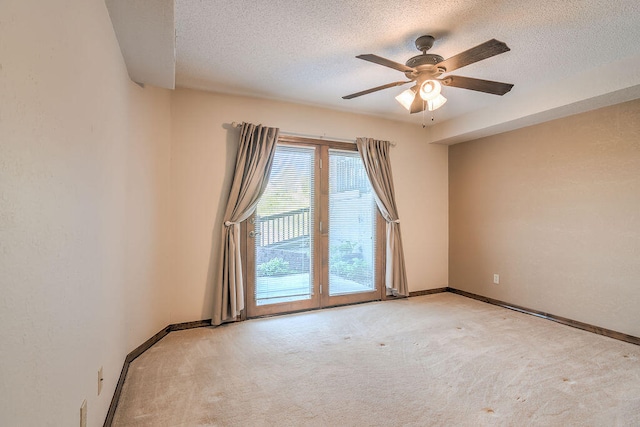 empty room with ceiling fan, light colored carpet, and a textured ceiling