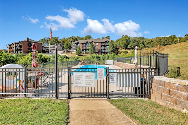 view of gate featuring a community pool and a yard