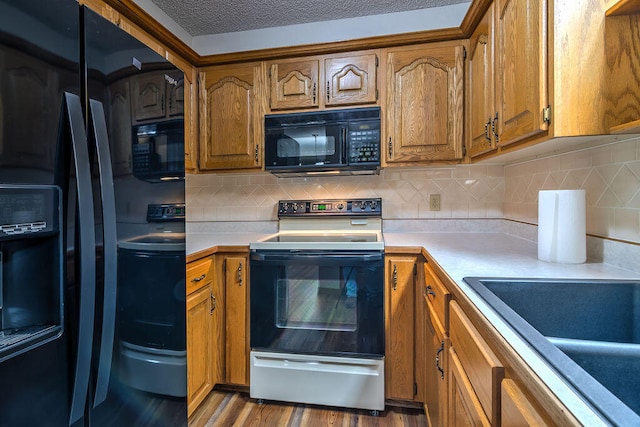 kitchen with sink, a textured ceiling, dark wood-type flooring, black appliances, and decorative backsplash