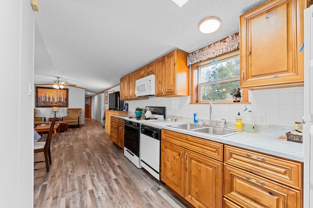 kitchen with lofted ceiling, sink, white appliances, wood-type flooring, and a textured ceiling