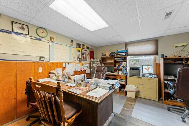 office with dark wood-type flooring, a drop ceiling, and wooden walls