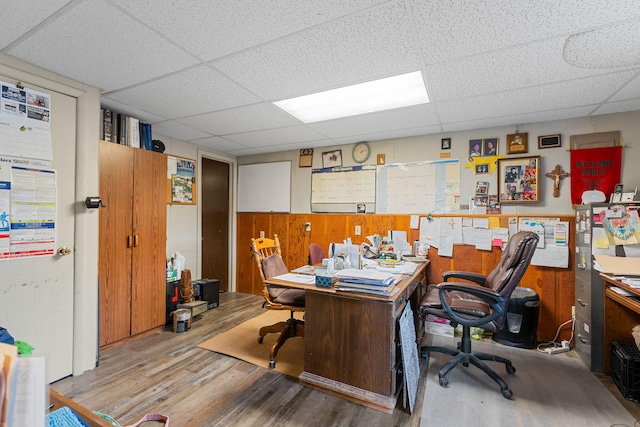 home office with a paneled ceiling, hardwood / wood-style flooring, and wooden walls