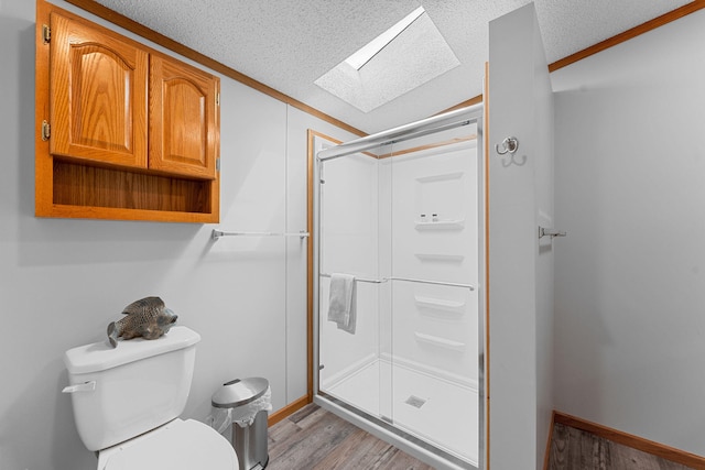 bathroom featuring hardwood / wood-style floors, an enclosed shower, a skylight, toilet, and a textured ceiling