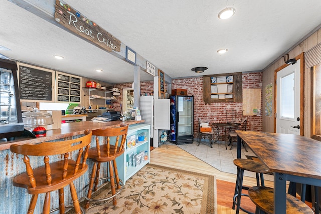 kitchen featuring brick wall, light hardwood / wood-style flooring, and a textured ceiling