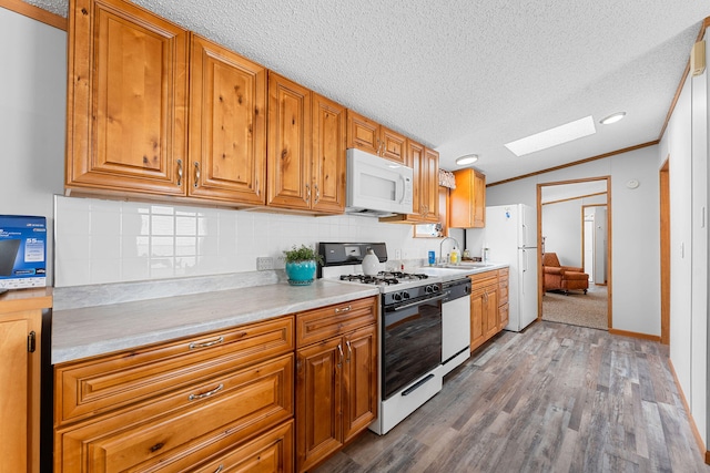 kitchen with white appliances, crown molding, dark wood-type flooring, sink, and a textured ceiling