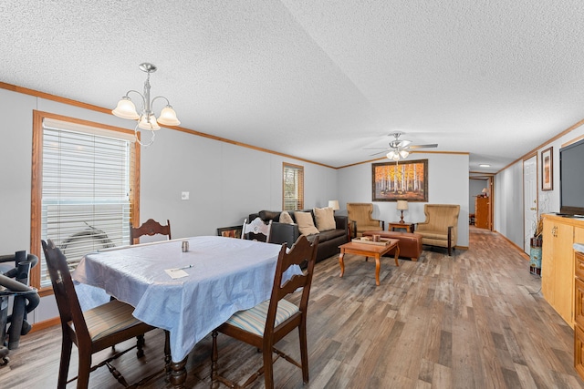 dining area featuring ceiling fan with notable chandelier, ornamental molding, hardwood / wood-style flooring, and a textured ceiling