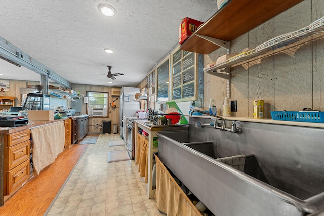 kitchen with ceiling fan, cooling unit, a textured ceiling, and stainless steel range oven