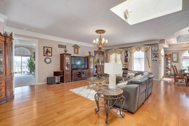 living room with light wood-type flooring, crown molding, and a chandelier