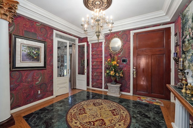 entryway with hardwood / wood-style flooring, crown molding, and a notable chandelier