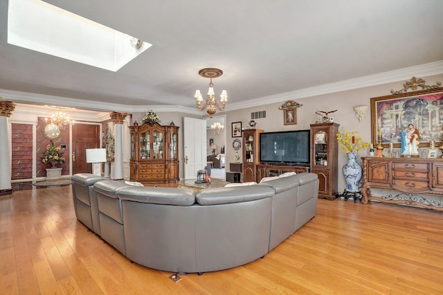 living room with a skylight, an inviting chandelier, light hardwood / wood-style flooring, and ornamental molding