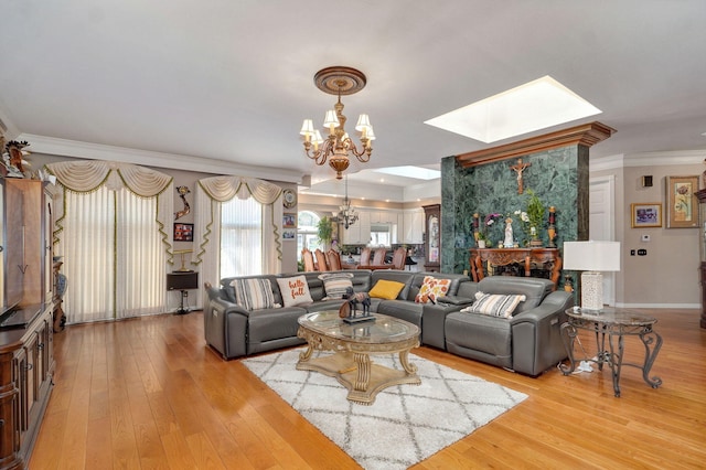 living room with a notable chandelier, crown molding, a skylight, and light hardwood / wood-style flooring