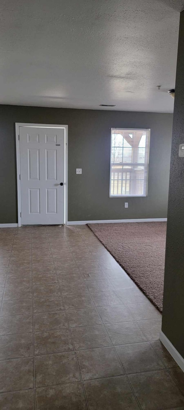 carpeted foyer entrance featuring a textured ceiling