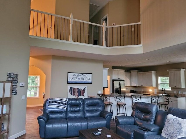 living room with a towering ceiling and light hardwood / wood-style flooring