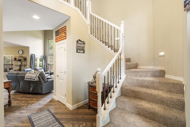 stairs featuring wood-type flooring and a towering ceiling