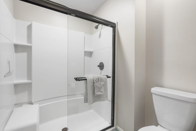 bathroom with a shower with shower door and toilet